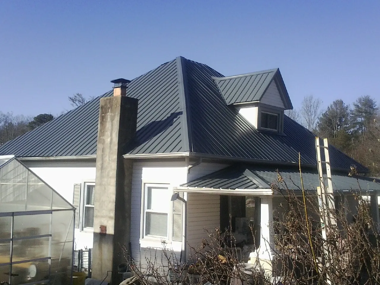 Dark blue standing seam metal roof on a white farmhouse with dormer — Slate & Tile Roof Repair by Roofing Brothers in Eubank