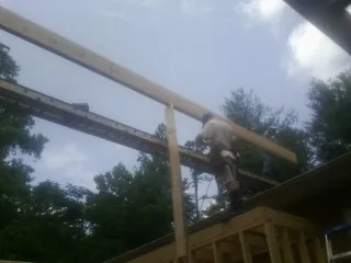 Carpenter setting a ridge beam over a new addition frame — Ice Dam Removal by Roofing Brothers in Eubank