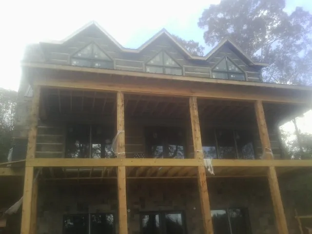 Dormers and porch framing on a large log home under construction — Roof Coating work by our crew in Eubank