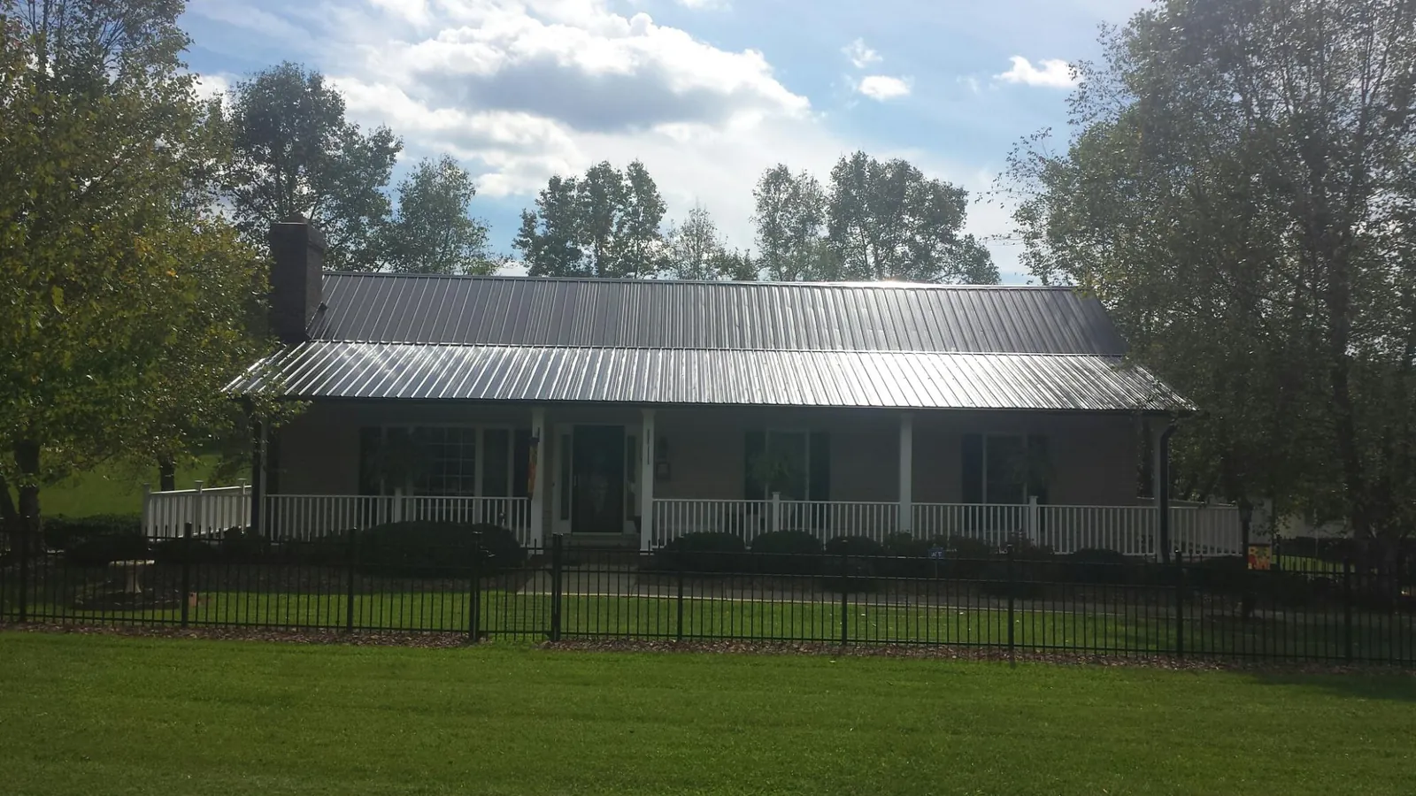 Gray metal roof on a brick ranch with a full width front porch — Gutter Guard Installation work by our crew in Eubank