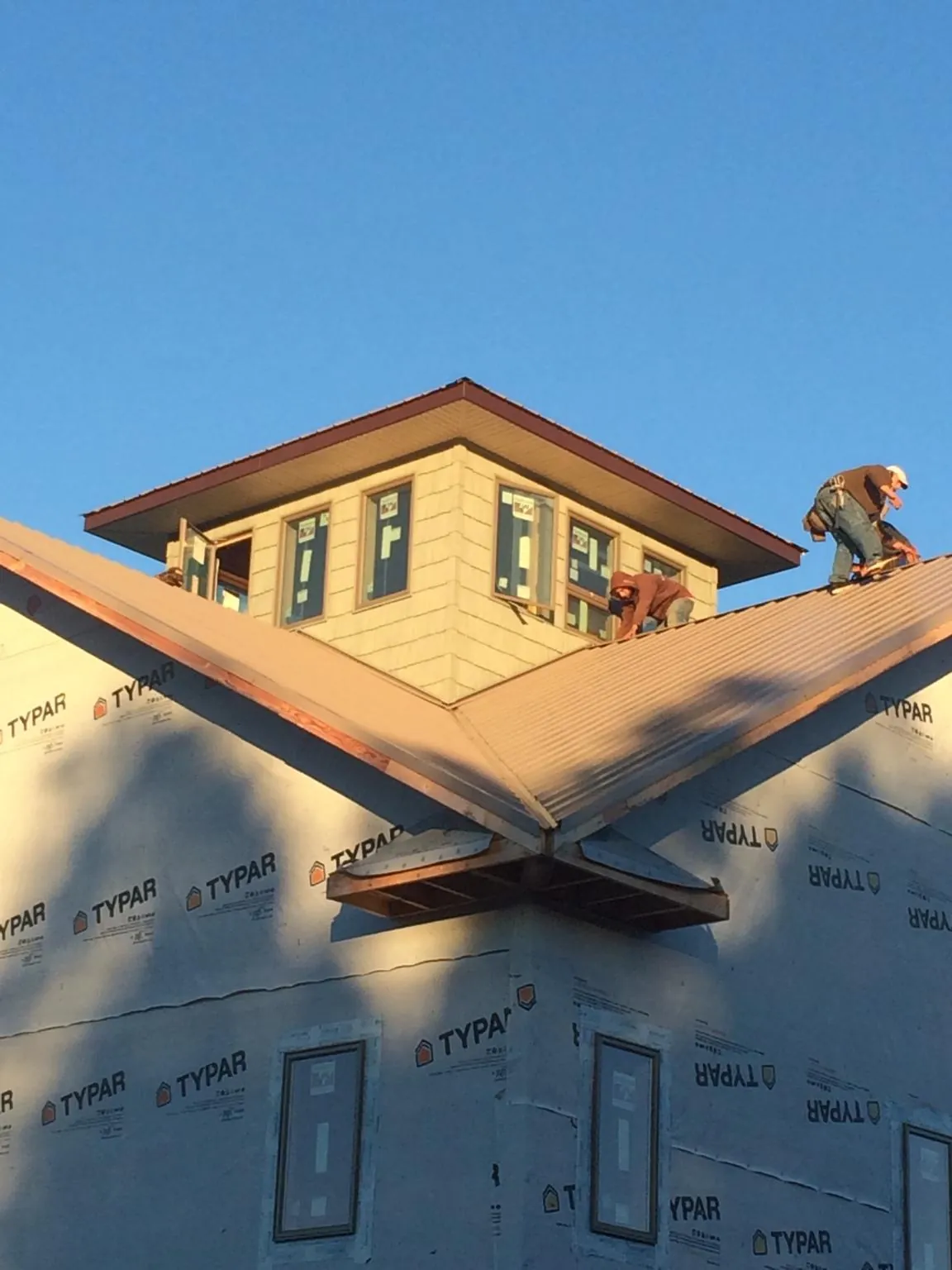 Roofers working around a rooftop cupola on a new metal roof at sunset — Roof Waterproofing in Eubank by Roofing Brothers